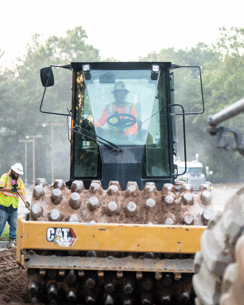 APCC, Employee operating sheeps foot roller, two employees in hard hats and safety vests on left side background, 23137_BUILDWITT_0274